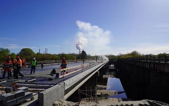 Выравнивающий слой цементобетона укладывают рабочие на новый мост в Фокино